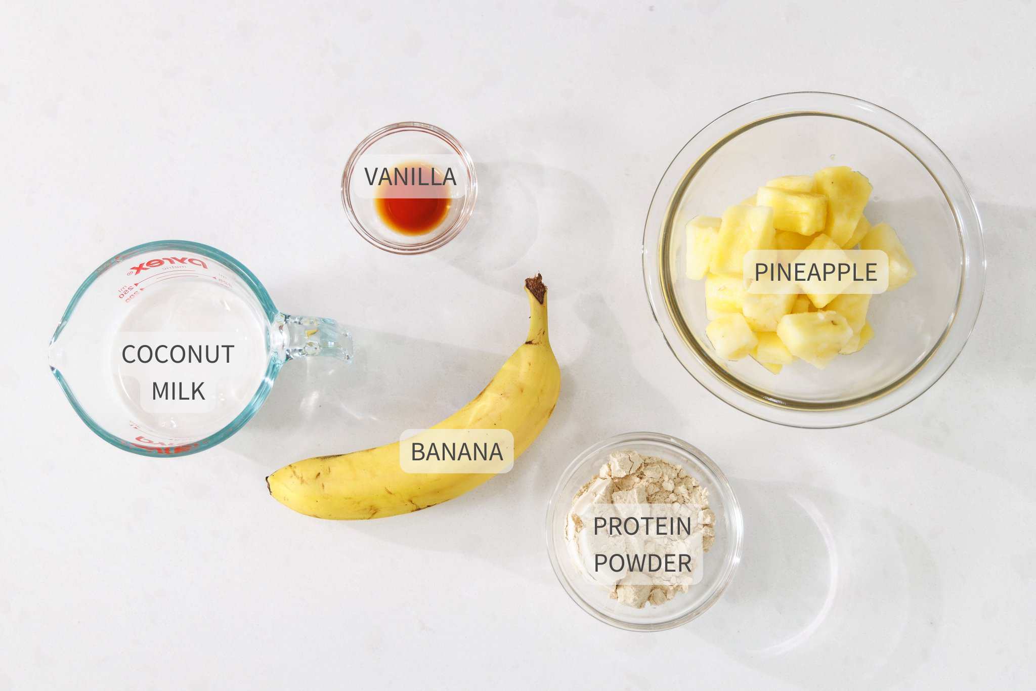 Labeled ingredients for pina colada protein smoothie on a counter.