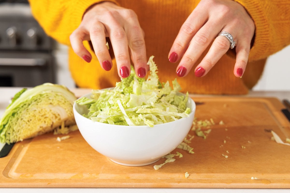 Putting shredded cabbage in a bowl.