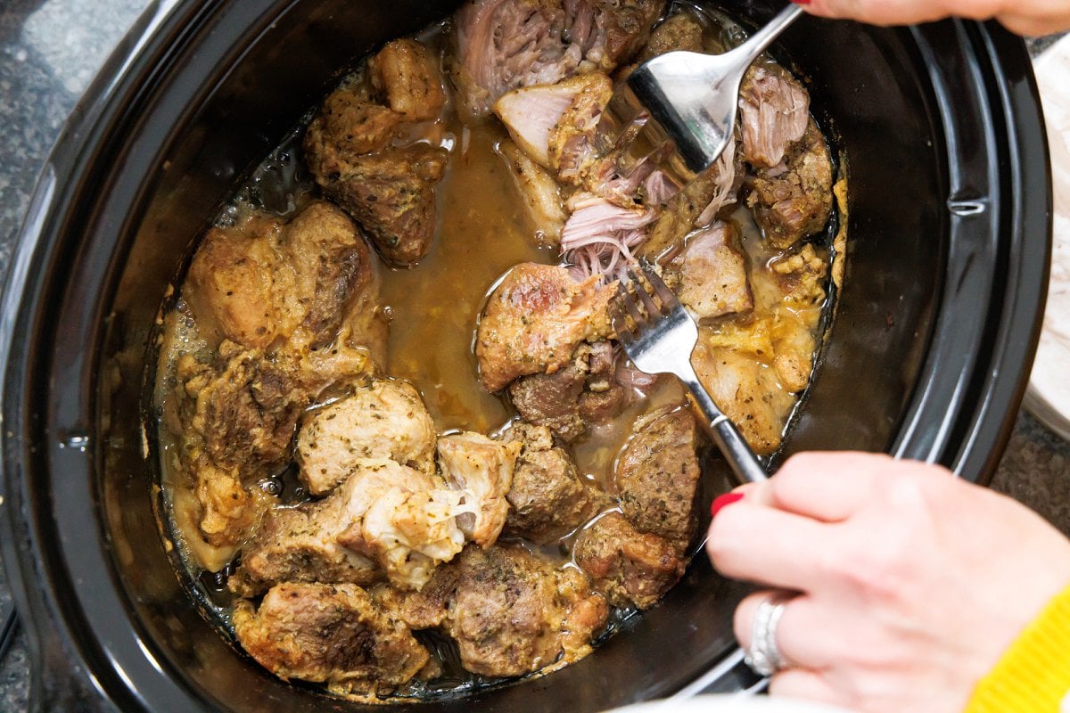 Cooked pork carnitas in the pot of a slow cooker.
